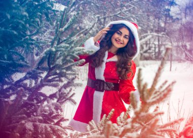 Genç Arap kadın kış günü, güzel bir Noel Baba ceketiyle karlı bir bahçede.