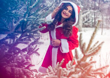 Genç Arap kadın kış günü, güzel bir Noel Baba ceketiyle karlı bir bahçede.