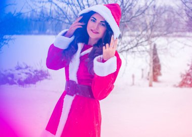 Genç Arap kadın kış günü, güzel bir Noel Baba ceketiyle karlı bir bahçede.