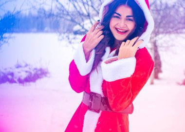 Genç Arap kadın kış günü, güzel bir Noel Baba ceketiyle karlı bir bahçede.