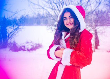 Genç Arap kadın kış günü, güzel bir Noel Baba ceketiyle karlı bir bahçede.