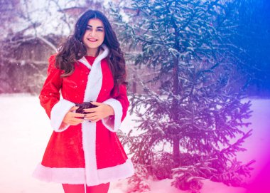 Genç Arap kadın kış günü, güzel bir Noel Baba ceketiyle karlı bir bahçede.