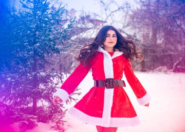 Genç Arap kadın kış günü, güzel bir Noel Baba ceketiyle karlı bir bahçede.