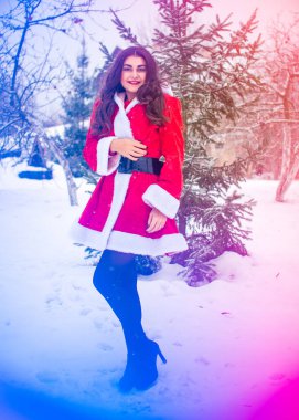 Genç Arap kadın kış günü, güzel bir Noel Baba ceketiyle karlı bir bahçede.