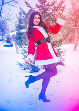 Genç Arap kadın kış günü, güzel bir Noel Baba ceketiyle karlı bir bahçede.