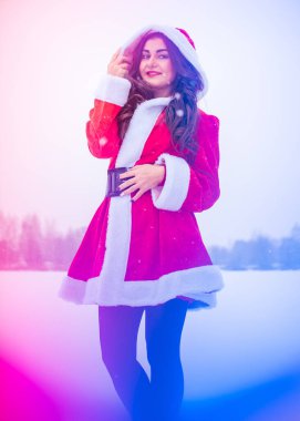 Genç Arap kadın kış günü, güzel bir Noel Baba ceketiyle karlı bir bahçede.