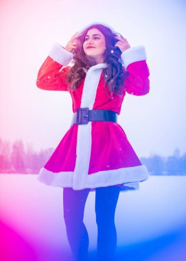 Genç Arap kadın kış günü, güzel bir Noel Baba ceketiyle karlı bir bahçede.