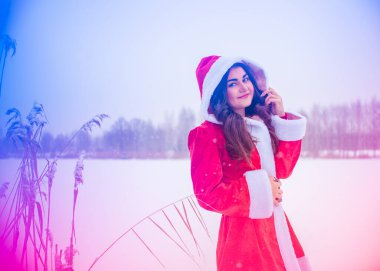 Genç Arap kadın kış günü, güzel bir Noel Baba ceketiyle karlı bir bahçede.