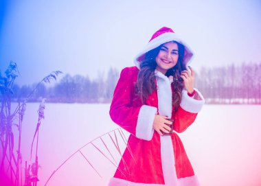 Genç Arap kadın kış günü, güzel bir Noel Baba ceketiyle karlı bir bahçede.