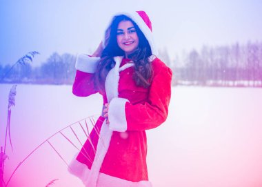 Genç Arap kadın kış günü, güzel bir Noel Baba ceketiyle karlı bir bahçede.