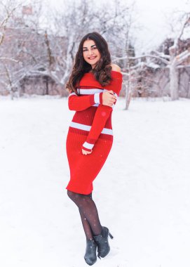 Karlı kış gününde siyah saçlı, örgü kırmızısı elbiseli İspanyol bir kadın. Sıradan moda anlayışı.