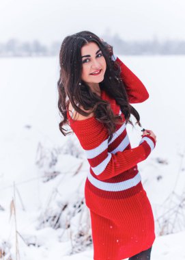 Karlı kış gününde siyah saçlı, örgü kırmızısı elbiseli İspanyol bir kadın. Sıradan moda anlayışı.