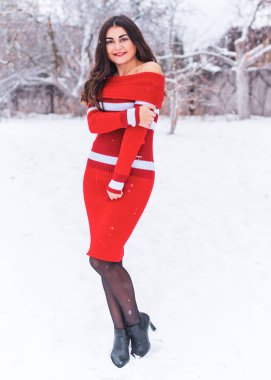 Karlı kış gününde siyah saçlı, örgü kırmızısı elbiseli İspanyol bir kadın. Sıradan moda anlayışı.