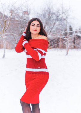 Karlı kış gününde siyah saçlı, örgü kırmızısı elbiseli İspanyol bir kadın. Sıradan moda anlayışı.