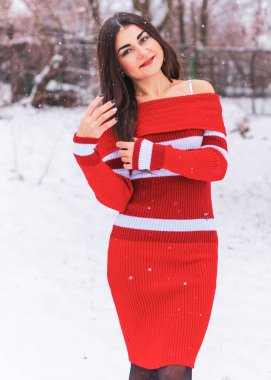 Karlı kış gününde siyah saçlı, örgü kırmızısı elbiseli İspanyol bir kadın. Sıradan moda anlayışı.