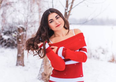 Karlı kış gününde siyah saçlı, örgü kırmızısı elbiseli İspanyol bir kadın. Sıradan moda anlayışı.