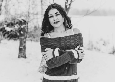 Karlı kış gününde siyah saçlı, örgü kırmızısı elbiseli İspanyol bir kadın. Sıradan moda anlayışı.