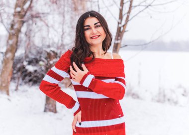 Karlı kış gününde siyah saçlı, örgü kırmızısı elbiseli İspanyol bir kadın. Sıradan moda anlayışı.