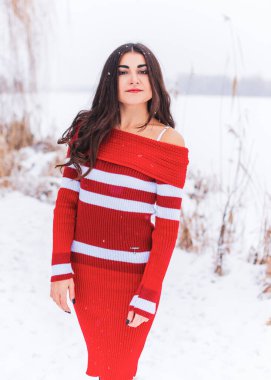 Karlı kış gününde siyah saçlı, örgü kırmızısı elbiseli İspanyol bir kadın. Sıradan moda anlayışı.