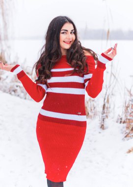 Karlı kış gününde siyah saçlı, örgü kırmızısı elbiseli İspanyol bir kadın. Sıradan moda anlayışı.