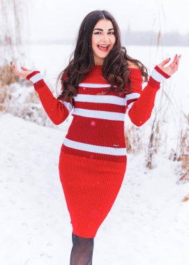 Karlı kış gününde siyah saçlı, örgü kırmızısı elbiseli İspanyol bir kadın. Sıradan moda anlayışı.