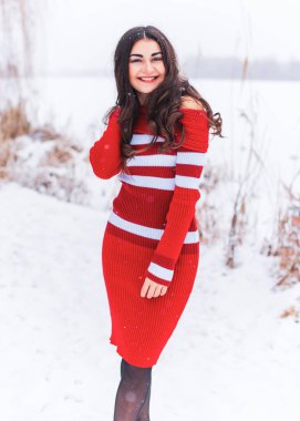 Karlı kış gününde siyah saçlı, örgü kırmızısı elbiseli İspanyol bir kadın. Sıradan moda anlayışı.