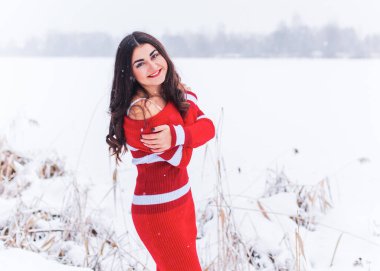 Karlı kış gününde siyah saçlı, örgü kırmızısı elbiseli İspanyol bir kadın. Sıradan moda anlayışı.