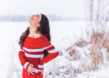 Karlı kış gününde siyah saçlı, örgü kırmızısı elbiseli İspanyol bir kadın. Sıradan moda anlayışı.