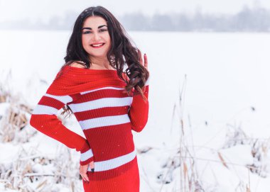 Karlı kış gününde siyah saçlı, örgü kırmızısı elbiseli İspanyol bir kadın. Sıradan moda anlayışı.