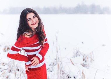 Karlı kış gününde siyah saçlı, örgü kırmızısı elbiseli İspanyol bir kadın. Sıradan moda anlayışı.