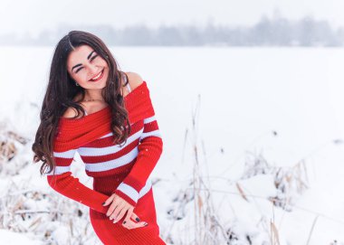 Karlı kış gününde siyah saçlı, örgü kırmızısı elbiseli İspanyol bir kadın. Sıradan moda anlayışı.