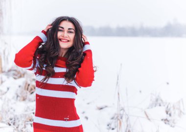 Karlı kış gününde siyah saçlı, örgü kırmızısı elbiseli İspanyol bir kadın. Sıradan moda anlayışı.