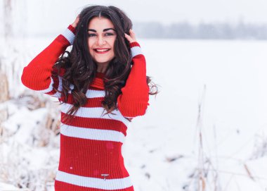 Karlı kış gününde siyah saçlı, örgü kırmızısı elbiseli İspanyol bir kadın. Sıradan moda anlayışı.