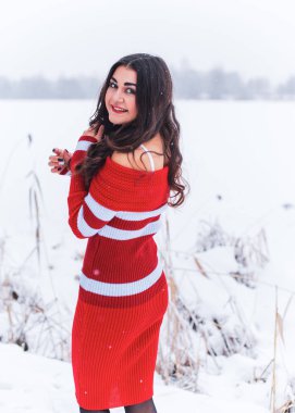 Karlı kış gününde siyah saçlı, örgü kırmızısı elbiseli İspanyol bir kadın. Sıradan moda anlayışı.