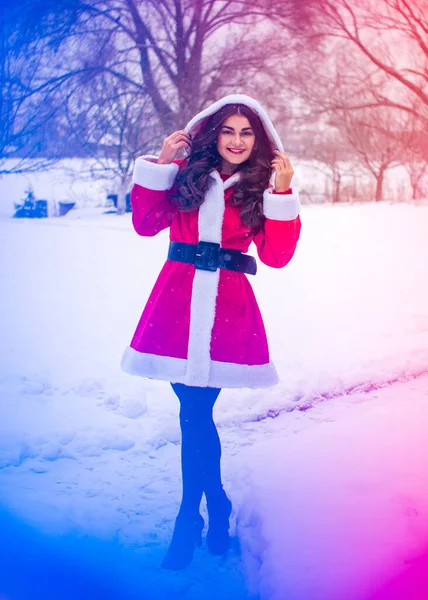 Genç Arap kadın kış günü, güzel bir Noel Baba ceketiyle karlı bir bahçede.