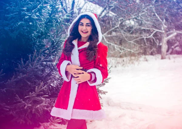 若いですアラビア人女性で冬の日にかなりサンタコートで雪の庭 — ストック写真