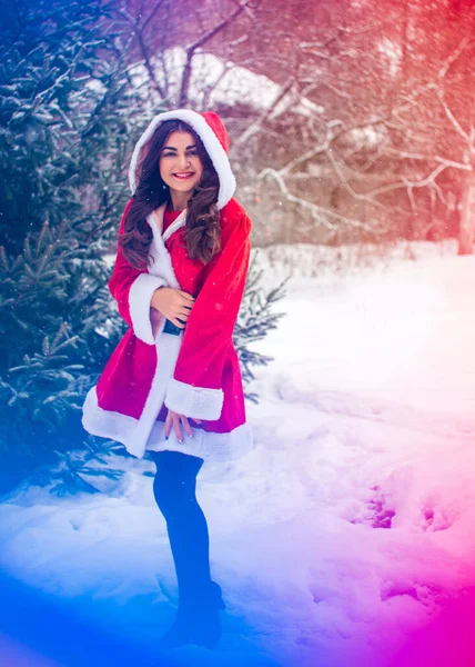 Genç Arap kadın kış günü, güzel bir Noel Baba ceketiyle karlı bir bahçede.