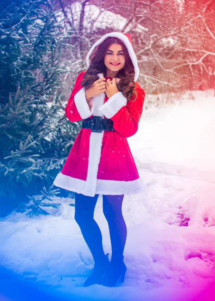 Genç Arap kadın kış günü, güzel bir Noel Baba ceketiyle karlı bir bahçede.