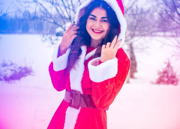 若いですアラビア人女性で冬の日にかなりサンタコートで雪の庭 — ストック写真