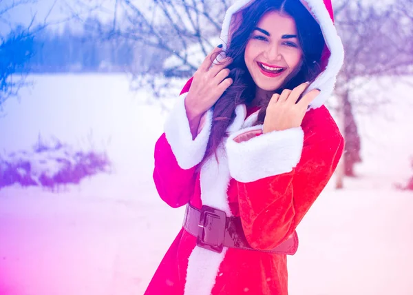 Genç Arap kadın kış günü, güzel bir Noel Baba ceketiyle karlı bir bahçede.