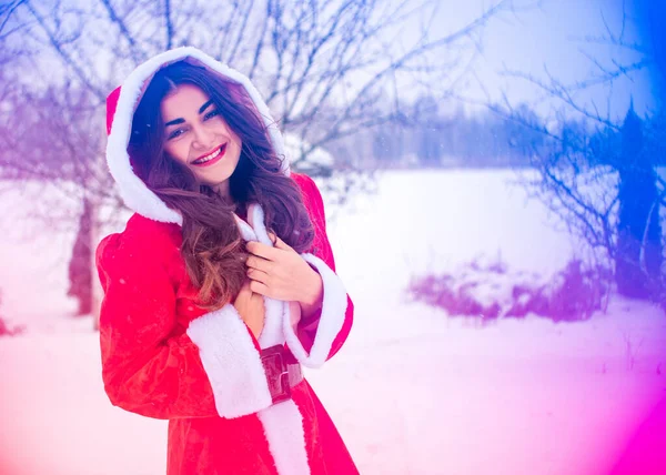 Genç Arap kadın kış günü, güzel bir Noel Baba ceketiyle karlı bir bahçede.