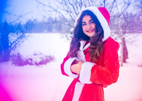 Genç Arap kadın kış günü, güzel bir Noel Baba ceketiyle karlı bir bahçede.