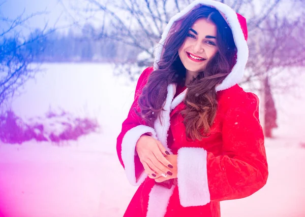 Genç Arap kadın kış günü, güzel bir Noel Baba ceketiyle karlı bir bahçede.