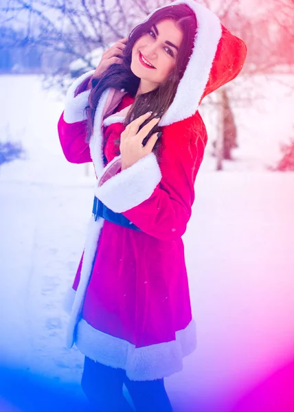 Genç Arap kadın kış günü, güzel bir Noel Baba ceketiyle karlı bir bahçede.