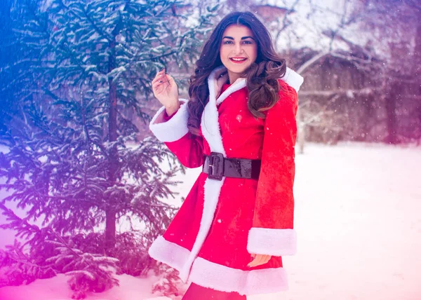 Genç Arap kadın kış günü, güzel bir Noel Baba ceketiyle karlı bir bahçede.