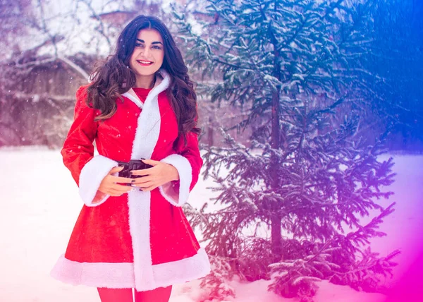 Genç Arap kadın kış günü, güzel bir Noel Baba ceketiyle karlı bir bahçede.