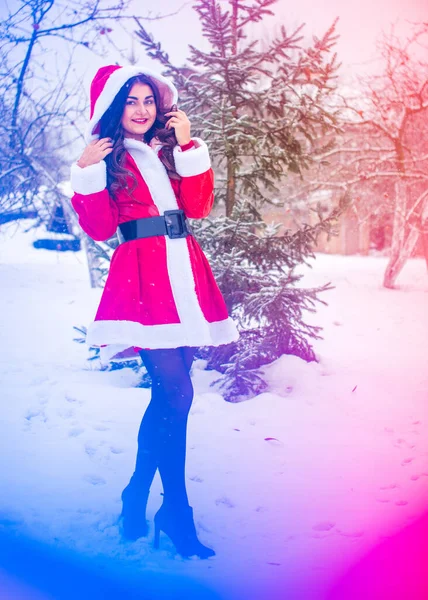 Genç Arap kadın kış günü, güzel bir Noel Baba ceketiyle karlı bir bahçede.