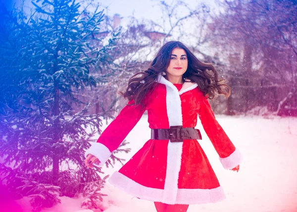 Genç Arap kadın kış günü, güzel bir Noel Baba ceketiyle karlı bir bahçede.
