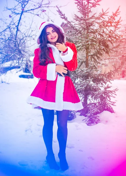 Genç Arap kadın kış günü, güzel bir Noel Baba ceketiyle karlı bir bahçede.