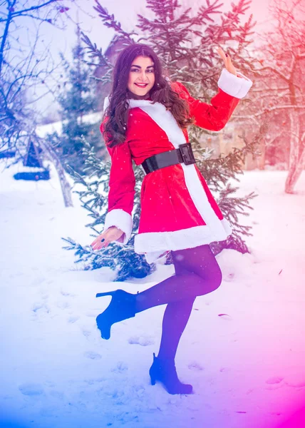 Genç Arap kadın kış günü, güzel bir Noel Baba ceketiyle karlı bir bahçede.